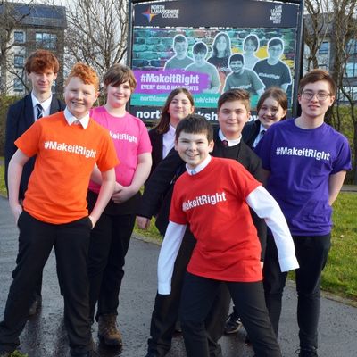 Make It Right, children's rights campaign. Young people posing in front of campaign billboard