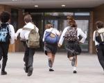 Children with backpacks running into school