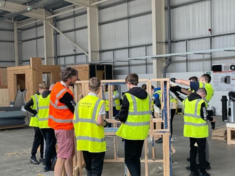 A group of people in hi-viz clothing, working in a joinery workshop